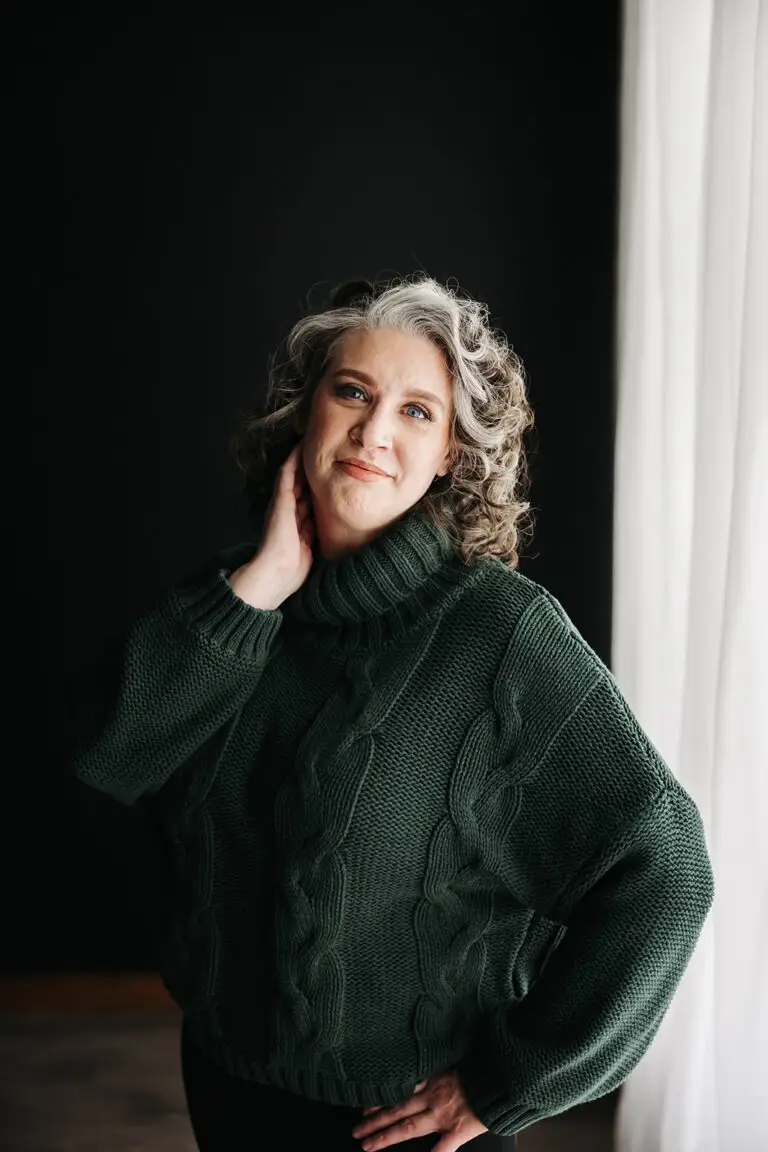 Coach Kristy standing by the window looking directly at the camera with a soft smile